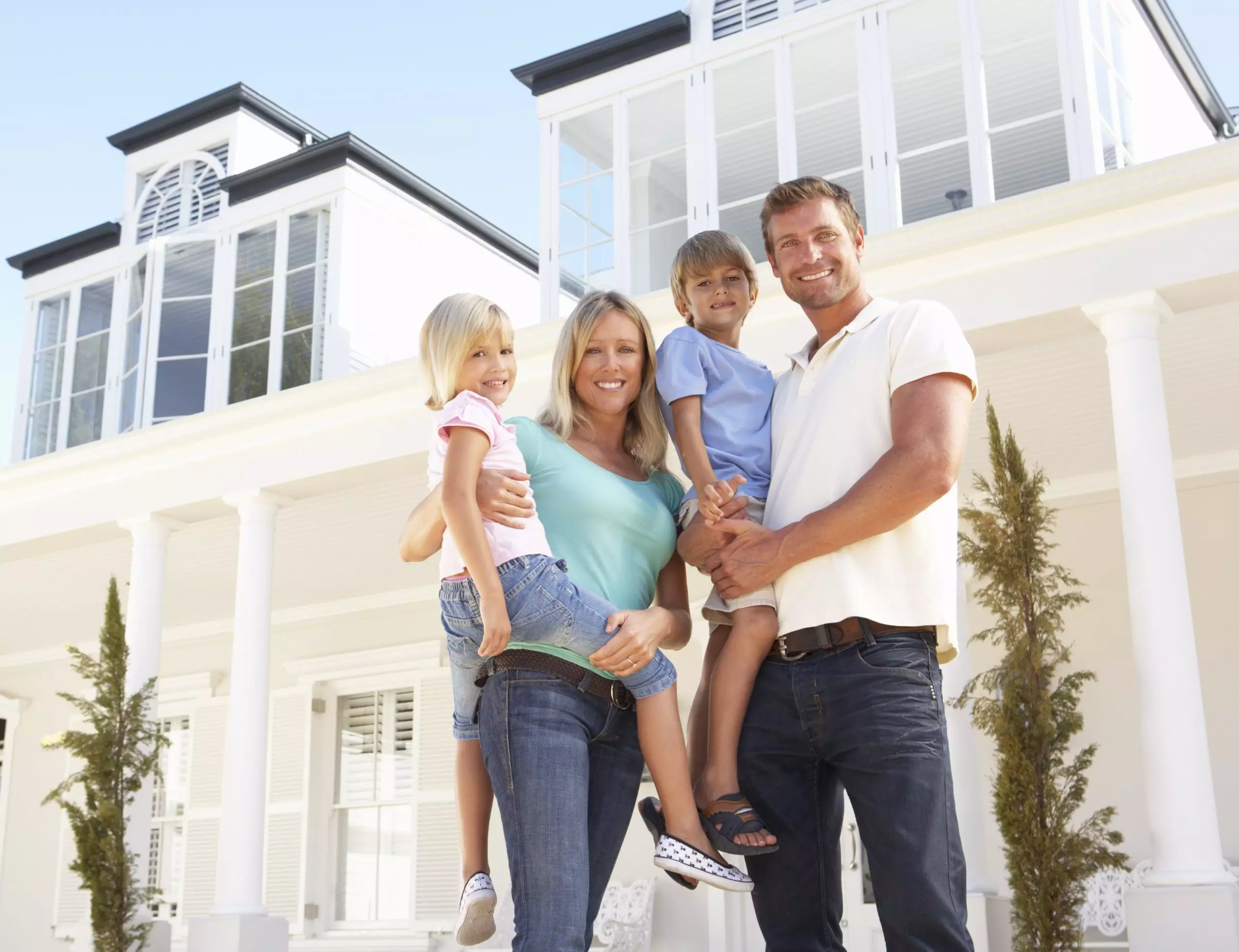 Young Family in front of large white home